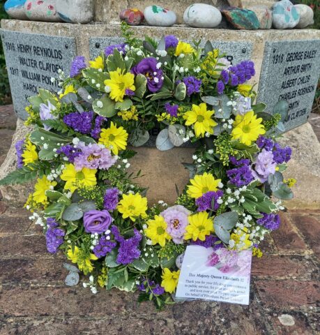 yellow and liliac coloured flowers in a circular wreath in memory of Queen Elizabeth II